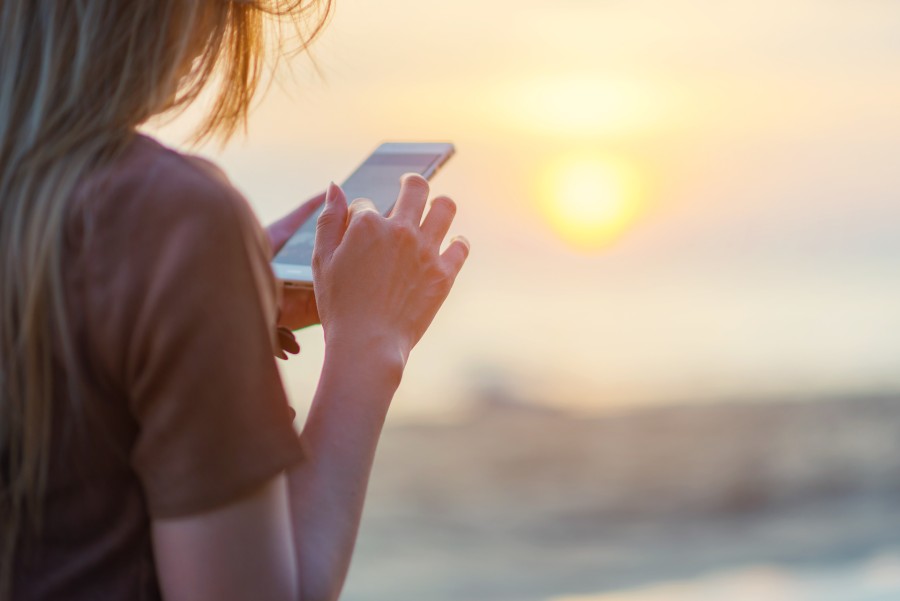 Female traveler booking activity on smartphone at beach