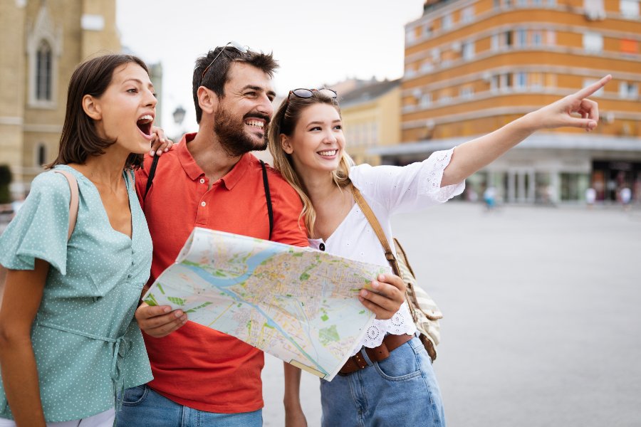 group of three travelers holding map and looking excited
